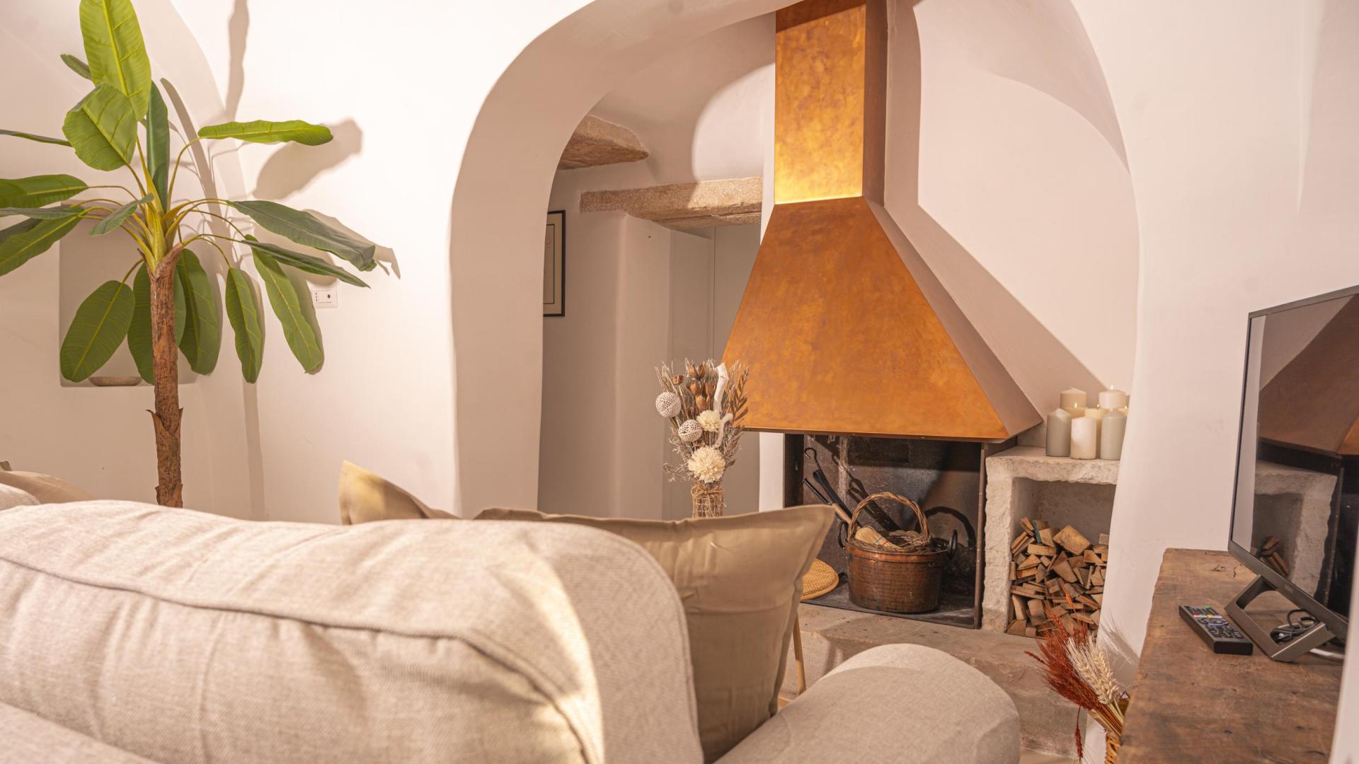 Cozy living room with fireplace, beige sofa, and decorative plant.