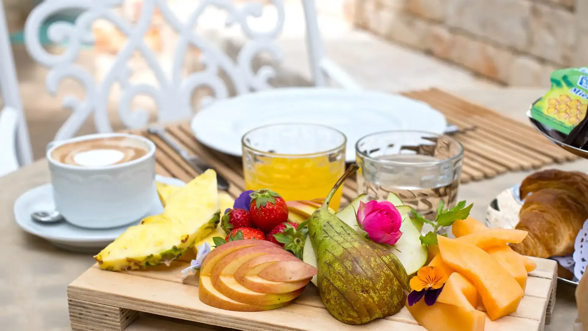 Petit-déjeuner avec fruits frais, jus, café et croissant.