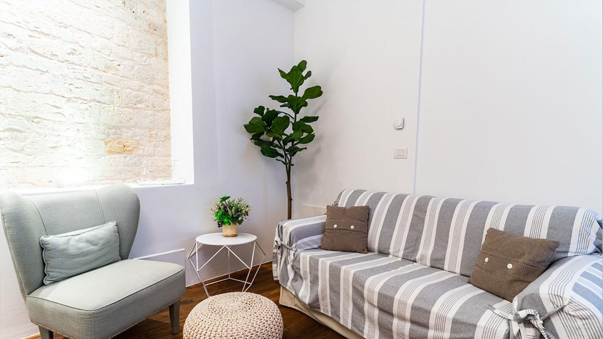 Salon confortable avec fauteuil, canapé, table d'appoint et plante décorative.