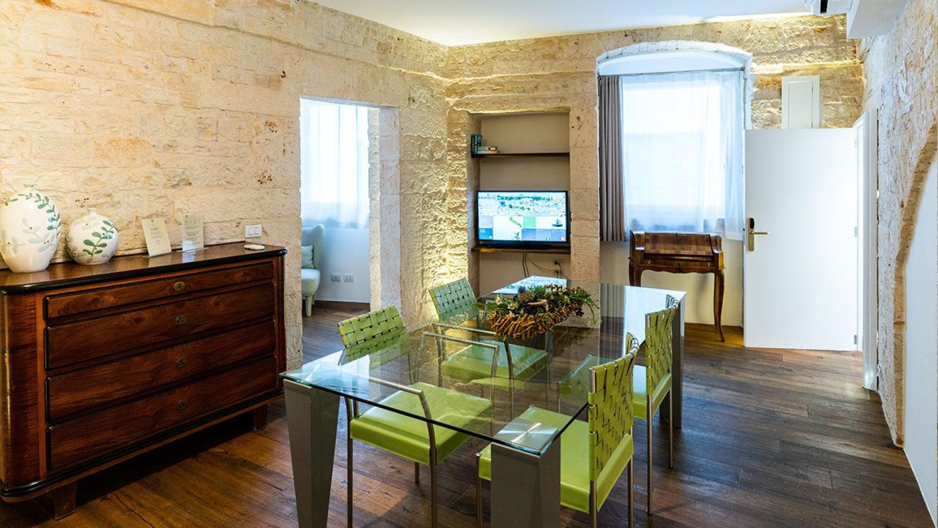 Salon chaleureux avec table en verre et murs en pierre.