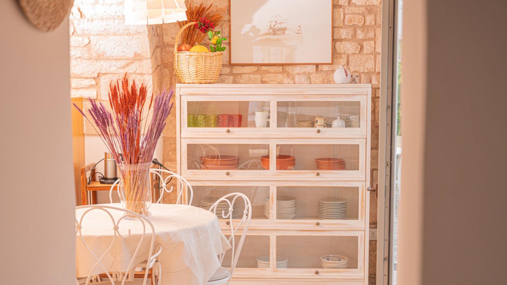 Sala da pranzo accogliente con tavolo rotondo e credenza bianca.