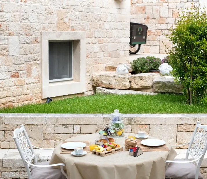 Petit-déjeuner en plein air dans une cour en pierre avec table dressée.