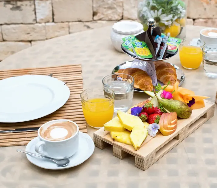 Petit déjeuner avec fruits, croissants, jus d'orange et café.