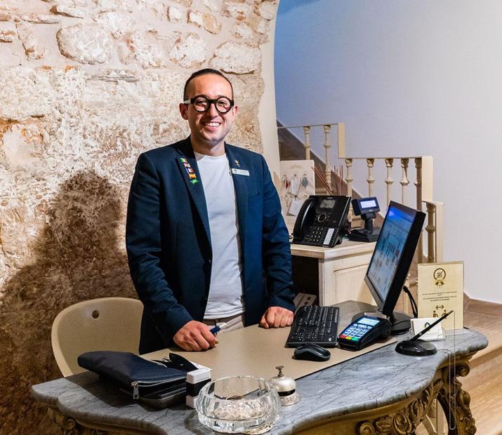Smiling receptionist in an office with stone walls and elegant furniture.