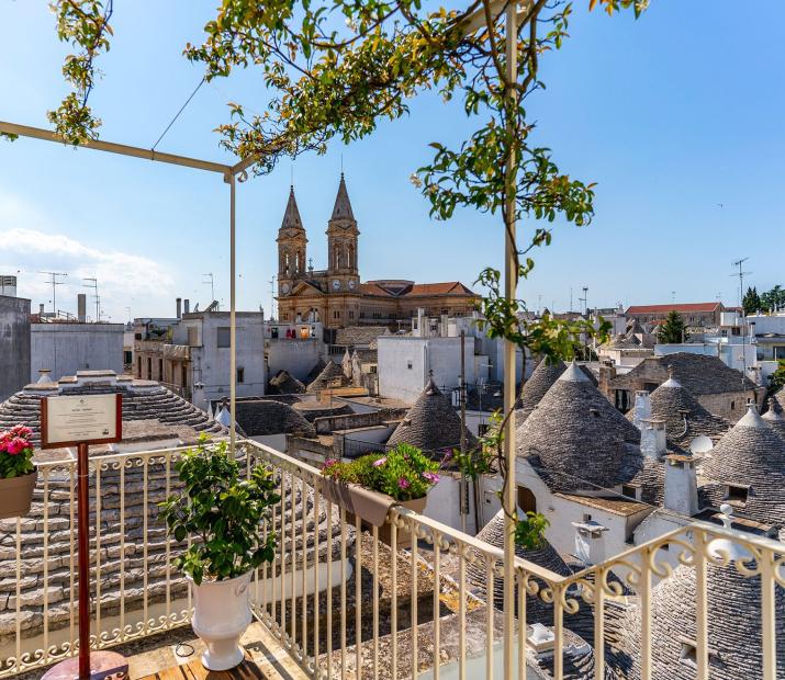 Vue panoramique d'Alberobello avec ses trulli emblématiques et une église en arrière-plan.