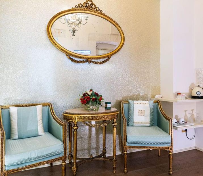 Salon élégant avec miroir doré, chaises bleues et table décorée.