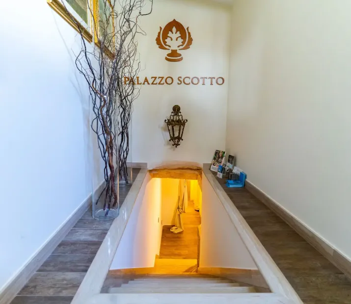 Interior staircase of Palazzo Scotto with decorations and informational brochures.