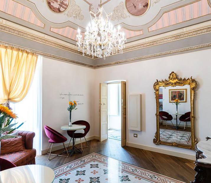 Salon élégant avec plafond fresqué, lustre en cristal et meubles raffinés.