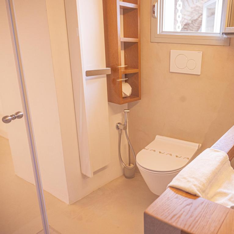 Modern bathroom with toilet, shower, and folded towels.