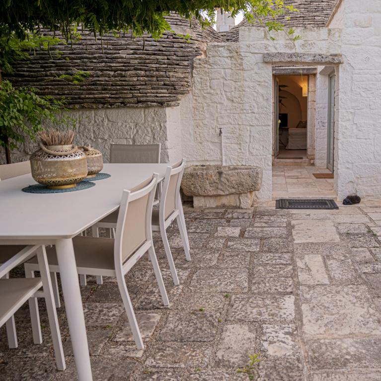 Courtyard with table, chairs, oven, and stone architecture.