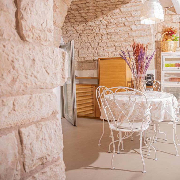 Rustic kitchen with round table, white chairs, and wooden cabinet.