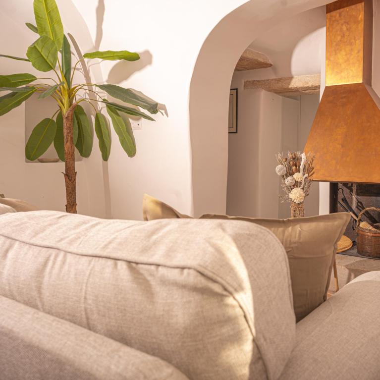 Salon confortable avec cheminée, canapé beige et plante décorative.