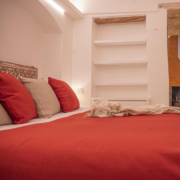 Cozy room with a red bed, white shelves, and rustic decorations.