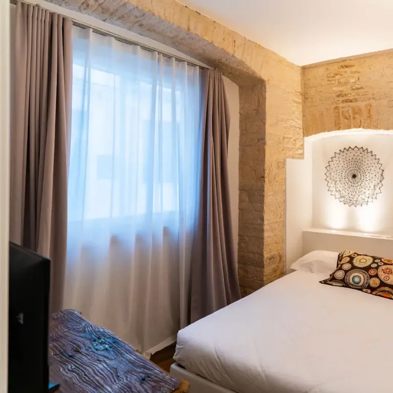 Chambre confortable avec murs en pierre, lit double et décorations artistiques.