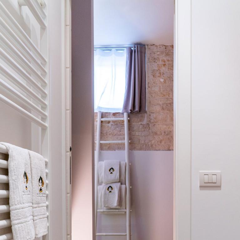 Salle de bain moderne avec serviettes blanches, murs en pierre et sol en bois.