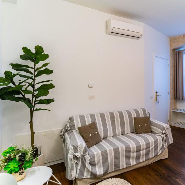 Salon confortable avec canapé rayé, cheminée et plante décorative.