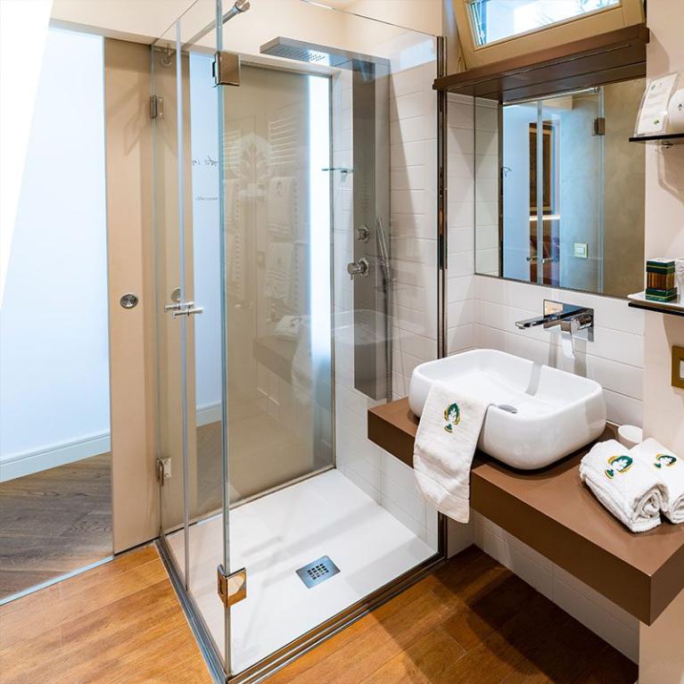 Modern bathroom with shower, floating sink, and white towels.