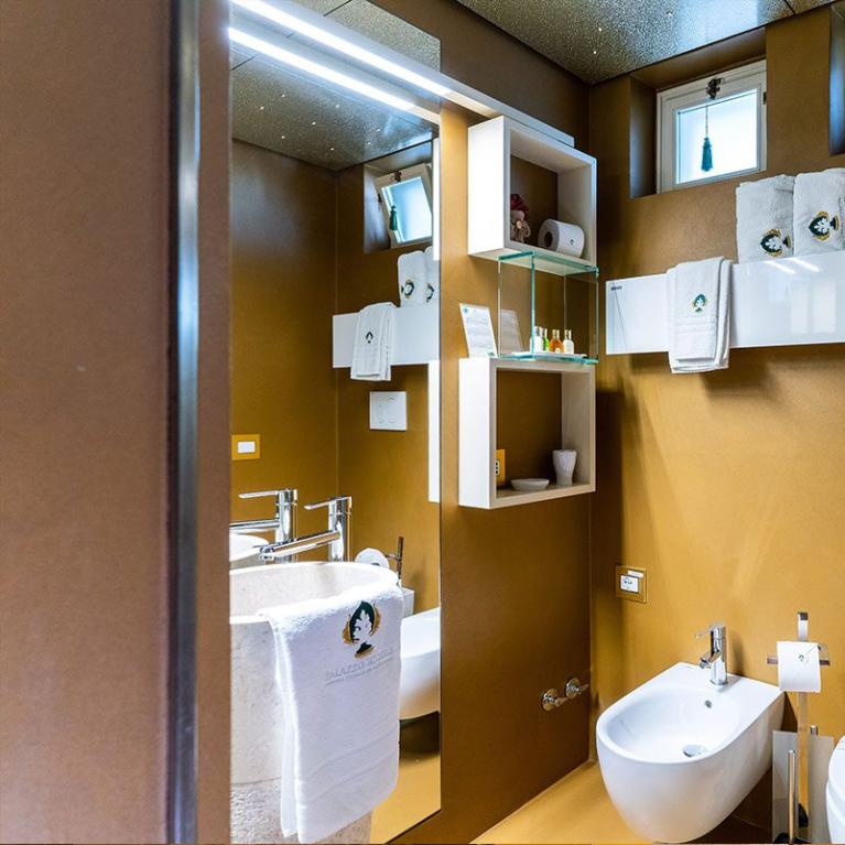 Modern bathroom with bidet, sink, large mirror, and white towels.