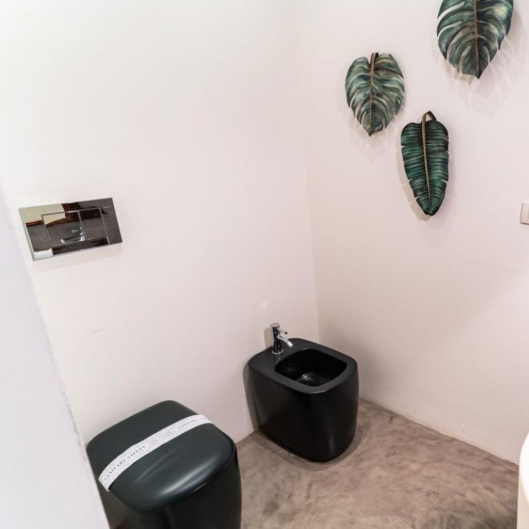 Salle de bain moderne avec bidet noir et décorations de feuilles.