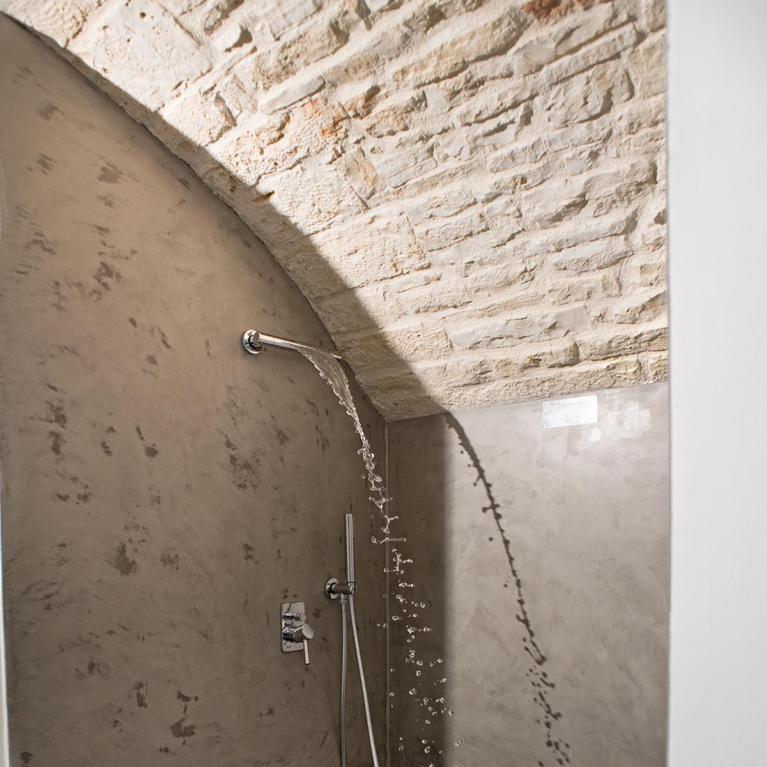 Douche moderne avec murs en béton et plafond en pierre.