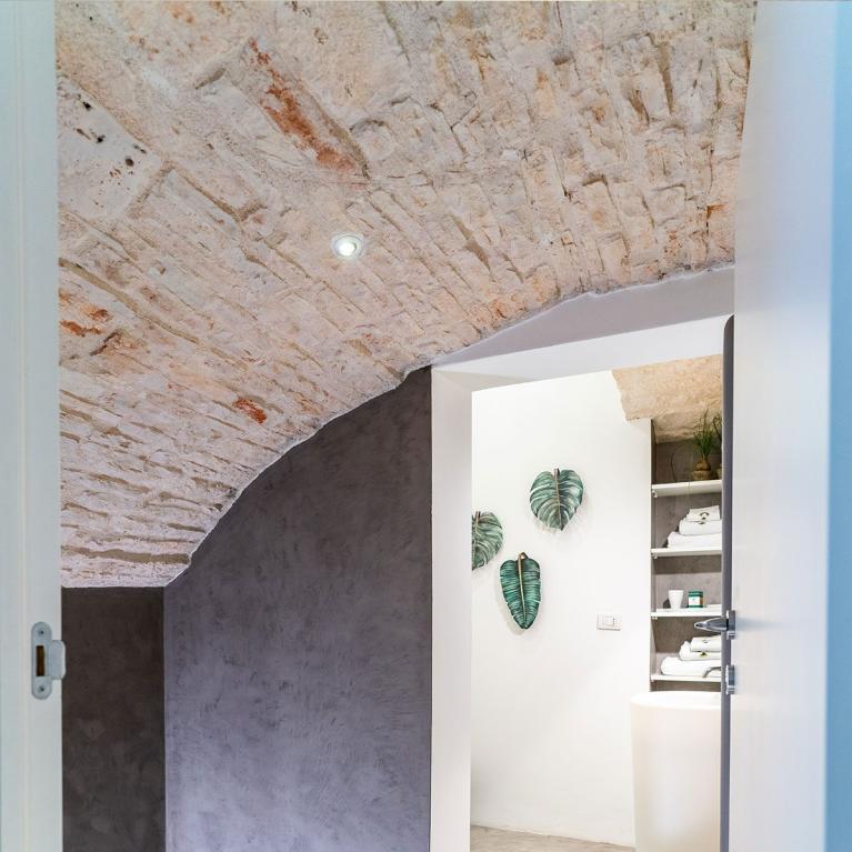 Salle de bain moderne avec murs en béton et plafond en briques apparentes.