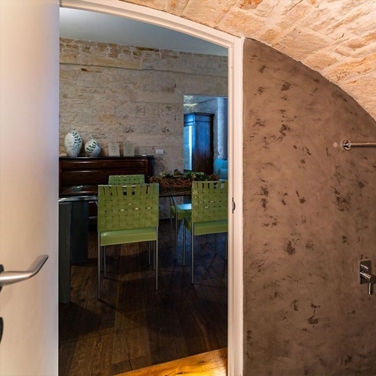 Douche moderne en pierre avec vue sur une salle à manger rustique.