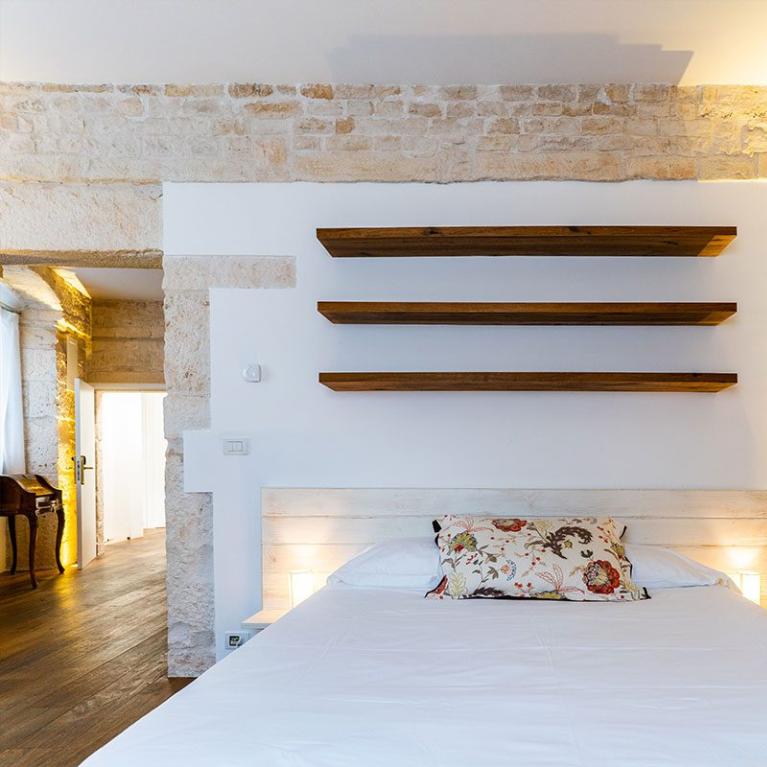 Chambre avec murs en pierre et étagères en bois.