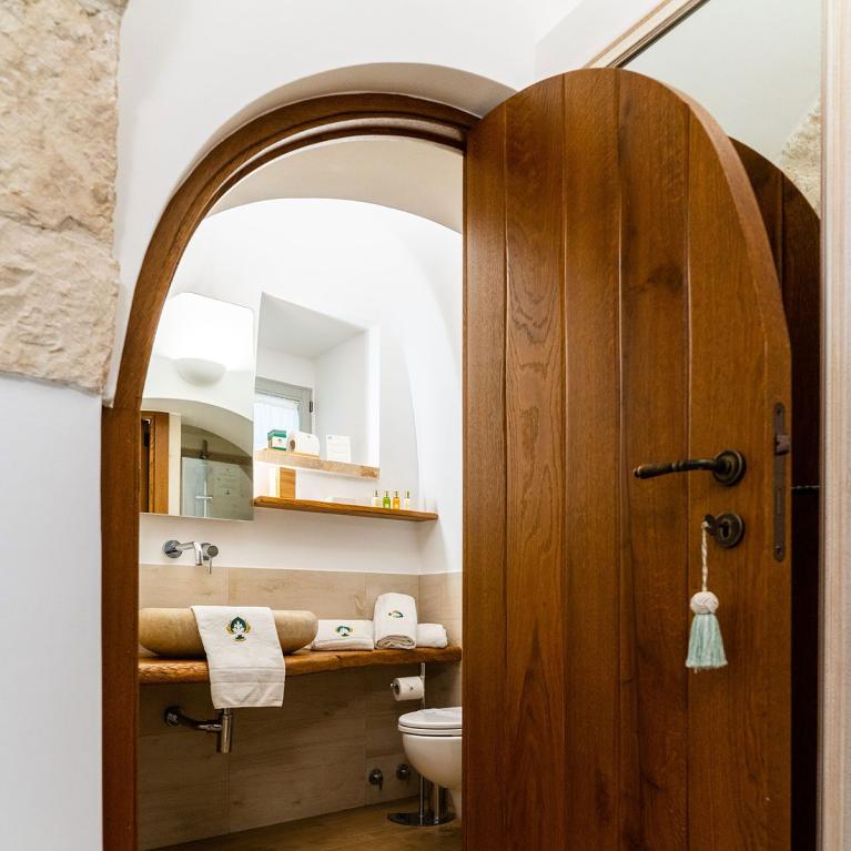 Salle de bain confortable avec porte en bois et lavabo en pierre.