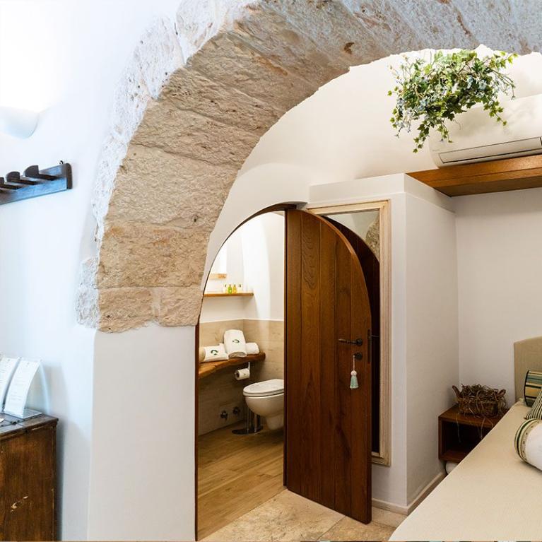 Chambre accueillante avec arche en pierre et salle de bain privée.